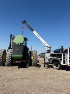 Boom crane lifting on a large articulated tractor in a field