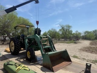 Crane lifting a front loader assembly off a tractor